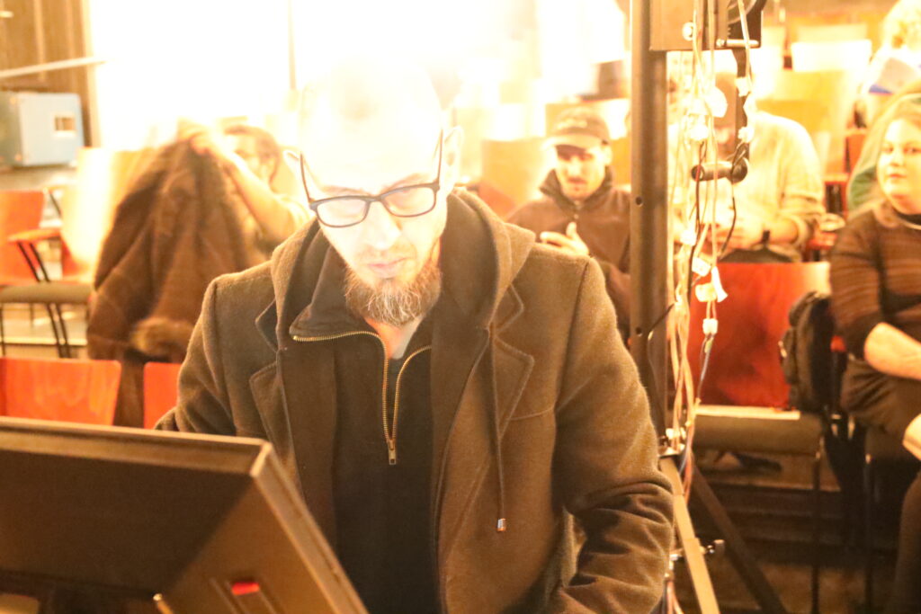 Performer working with modular synthesizers in a live electroacoustic context